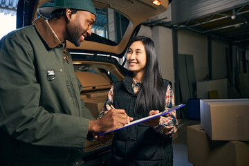 Young man and woman write in a folder while standing in a storage service