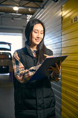 Smiling woman holding a blue folder in her hands while standing in a warehouse