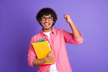 Photo of nice young man hold book raise fist wear pink shirt isolated on violet color background