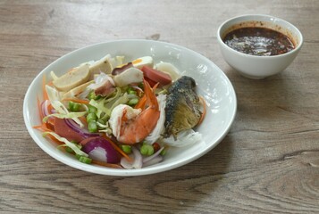 thin rice noodles with boiled shrimp squid slice sausage and mixed vegetable dressing spicy chili sauce Thai salad on plate