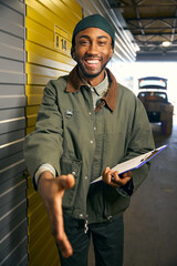 Smiling man stands in the storage service and extends his hand
