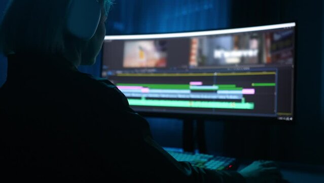 Unrecognizable graphic designer editing video project, working with timeline footage in editing software on ultrawide monitor. Concept of video processing, post-production. Shooting in slow motion.