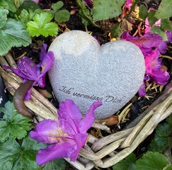 Ein Herz mit Blumen auf dem Friedhof mit Inschrift: ich vermisse dich.