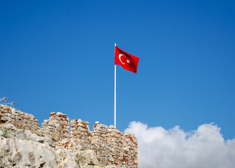 Turkey flag on top of an ancient stone wall against clear blue sky. Copy space for text, banner