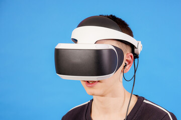A boy in a VR helmet on a blue background is going to play computer games.
