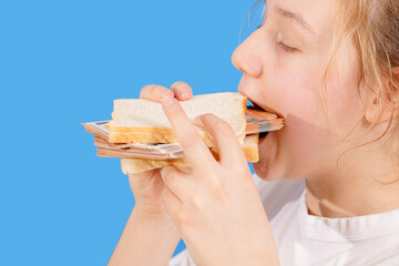 A girl eats a burger made from bread and banknotes.