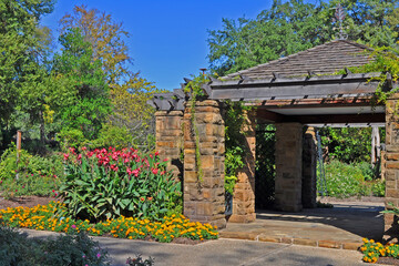 Sandstone Pavillion with shingle roof and trellis in botanic garden along walkway