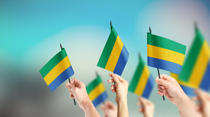 A group of people are holding small flags of Gabon in their hands.