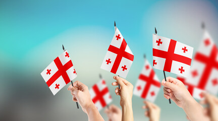 A group of people are holding small flags of Georgia in their hands.
