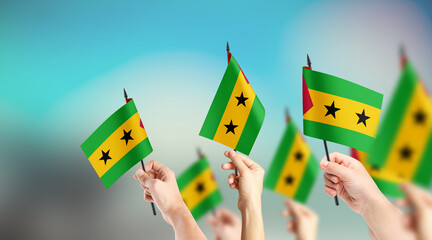 A group of people are holding small flags of São Tomé and Príncipe in their hands.