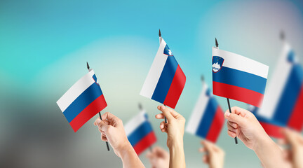 A group of people are holding small flags of Slovenia in their hands.