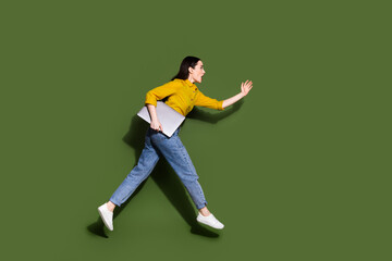 Full length photo of charming positive woman wear yellow shirt holding modern gadget jumping high isolated khaki color background