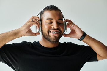 A stylish African American man smiling and wearing headphones on a vibrant backdrop.