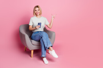 Photo of pretty adorable girl wear stylish grey clothes sit comfy chair empty space isolated on pink color background