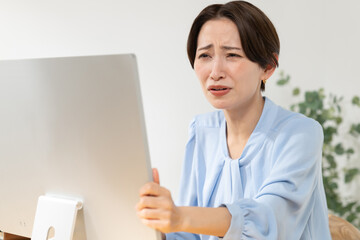 パソコンに向かって悩む女性