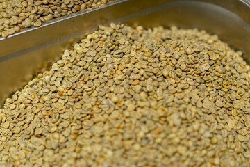 Obraz premium close up at small coffee roasting factory green coffee in iron containers preparing for roasting