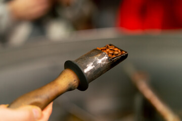 Close up of coffee holder in a roasting factory checking the roast level of the coffee ready to...