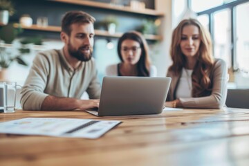 Three people are sitting at a table with a laptop open in front of them