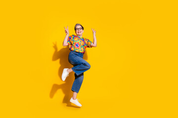 Fototapeta na wymiar Full body portrait of nice aged lady jump show v-sign wear t-shirt isolated on yellow color background