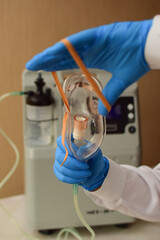 Hands in medical gloves hold out an oxygen mask against the background of the oxygen generator...