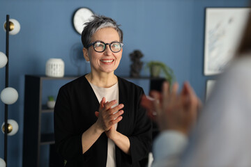 A successful and creative businesswoman claps with a smile, exuding confidence and leadership in...