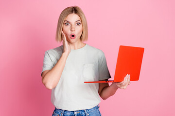 Portrait of stunned astonished girl with bob hair wear white t-shirt holding red laptop palm on...