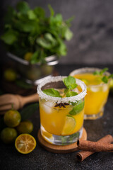 Fresh summer orange mojito with tangerine orange, mint and ice on black background