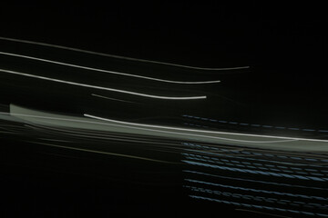 shows a long exposure photograph of light trails in the lamp. The trails are white and green, and...