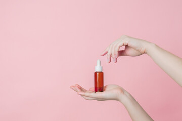 Fototapeta premium Hand holds serum glass brown bottle (essential oil) with pipette. Luxury product cosmetic advertising