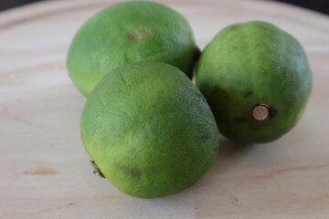 Una toma de cerca de tres limones verdes en una table de madera