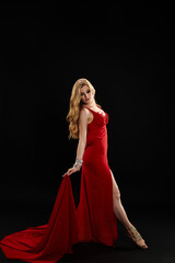 A graceful woman in a vibrant red dress strikes a pose.