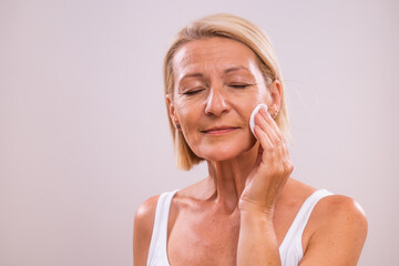 Portrait of beautiful mature woman  cleaning her face with cotton pad.