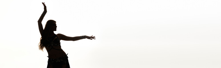 A woman in a flowing dress stands, arms raised in a joyful dance.