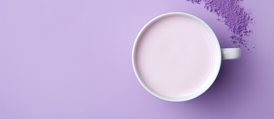 A white cup containing lavender moon milk is seen from a top view on a violet surface The image has...