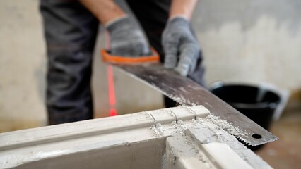 construction, Building manual work. A builder saws a concrete block with a hacksaw. Builder sawing aerated concrete block with hand saw at construction site.