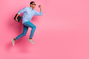 Full length photo of attractive funny guy wear plaid shirt jumping running holding modern gadget emtpy space isolated pink color background