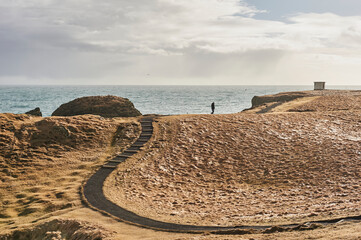 Icelandic destinations: A solitary person walks along the winding Hellnar-Arnarstapi trail, with...