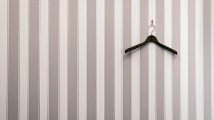 Hook with empty wooden cloth hanger on gray and white striped wall