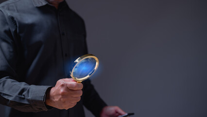 A man is holding a magnifying glass and looking at something. Concept of curiosity and investigation