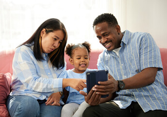 mixed race family using tablet online video call and taking selfie on sofa