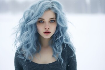 Portrait of a young woman with striking blue hair against a serene snowy backdrop