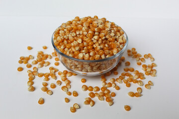 Dried corn kernels full in glass transparent bowl, isolated on white background