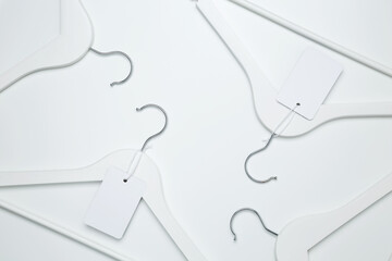 Creative flat lay hangers with white paper label. Clothing tag, label blank mockup template. Sale discount store promo shopping concept. Top view. Copy space