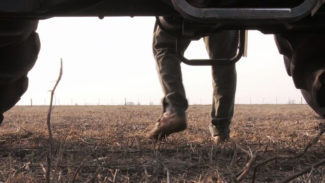 A Man Getting Out of his Tractor in an Agricultural Field. Low Angle View. Closeup. 4K Resolution.