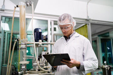 A man in a white lab coat is looking at a clipboard while wearing a white lab coat