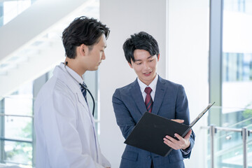 病院で笑顔で会話する男性医師と医薬情報担当者MR