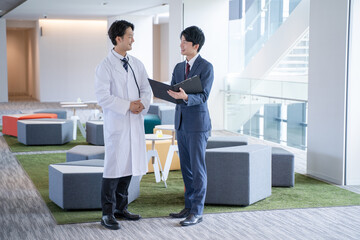 病院で笑顔で会話する男性医師と医薬情報担当者MR