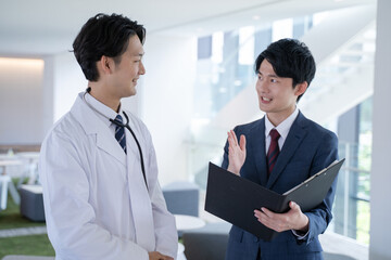 病院で笑顔で会話する男性医師と医薬情報担当者MR
