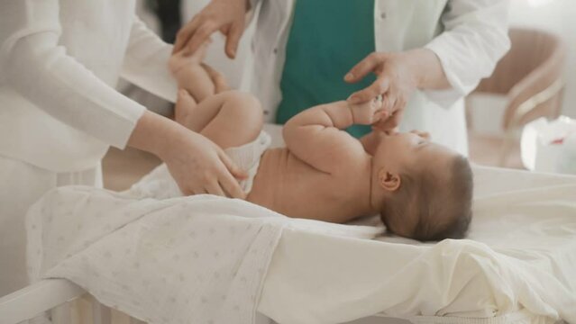 A mother changes diapers for her newborn baby
