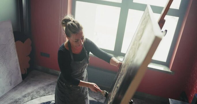 Woman in Apron Painting Leopard on Easel